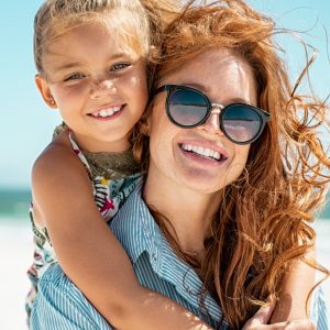 Young girl riding on mother's back at beach