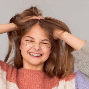Teen girl with braces smiling and holding her hair