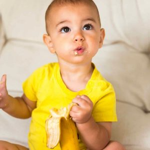 Baby holding and eating a banana