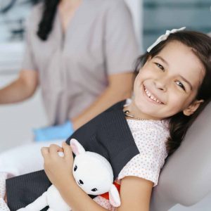 Young girl sitting in dentist chair smiling